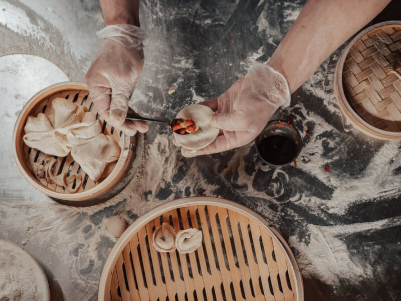 Hands placing fillings into homemade dumplings